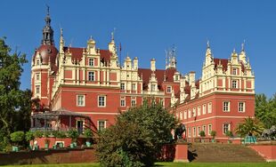Schloss Bad Muskau mit Treppe davor in grüner Parkanlage bei strahlendem Sonnenschein und blauem Himmel